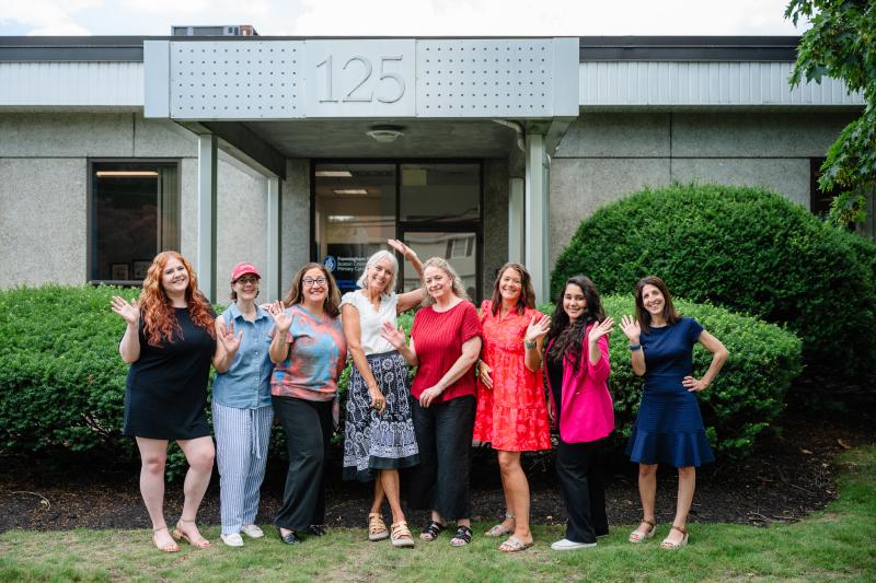 a group of eight women medical providers in front of a building